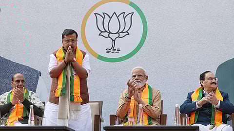 Nitin Nabin with PM Modi, JP Nadda and Rajhnath singh on the stage Nitin nabin is joining his hand the other are clapping, all are wearing BJP scarf and behind them is BJP Logo