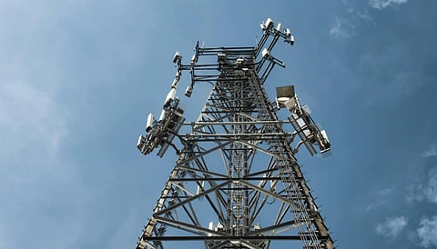 Tall communication tower against a clear blue sky, viewed from below. Steel framework with antennas, evoking technology and connectivity.