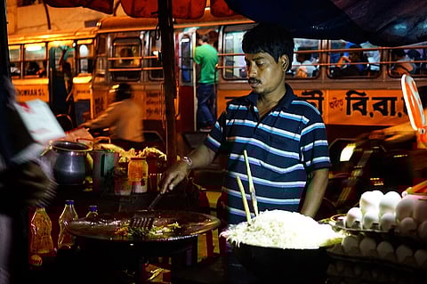 A hawker in Kolkata making noodles on a tawa on the streetside.
