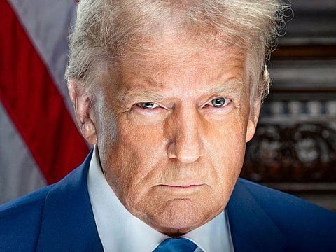 Portrait of US president Donald trump in his dark blue suit and blue tie. behind him a US flag is placed. 