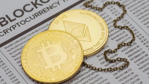 Two gold coins depicting Bitcoin and Ethereum on a newspaper with "BLOCKCHAIN CRYPTOCURRENCY" headline. A chain loops around them, symbolizing the digital economy.