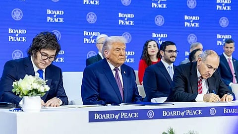 A group of world leaders in formal attire are seated at a "Board of Peace" event. 