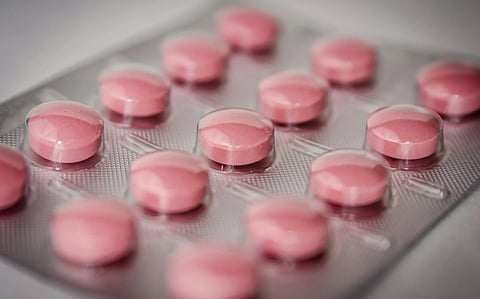 Close-up of a blister pack with pink round pills in clear plastic. The image conveys a clinical, pharmaceutical theme with an organized, neat appearance.