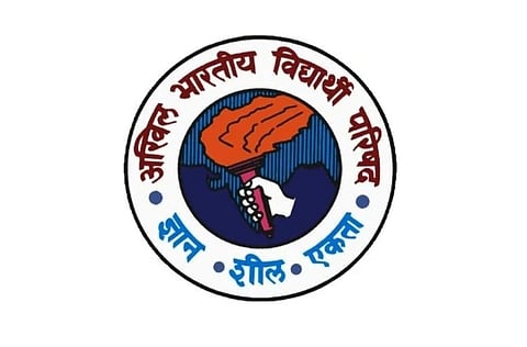 A logo featuring a torch over a map of India. Encircled by red Hindi text and blue dots, with blue Hindi words "ज्ञान," "शील," "एकता" at the bottom.