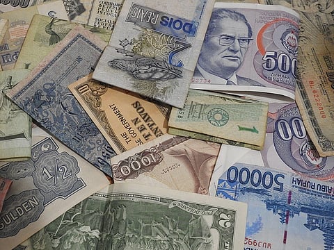 A set of past and present world currencies in a pile, entirely encompassed by the camera field of view.