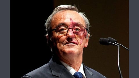 Dr Mariano Barbacid in a dark suit and blue tie speaks at a podium, with a microphone nearby. 
