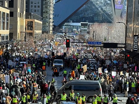 Thousands gather on the streets of Minneapolis, surrounded by buildings.