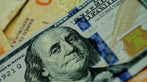 Close-up image of a 100 US dollar bill featuring Benjamin Franklin overlaid on colorful 1000-unit banknotes, conveying a theme of international currency exchange.
