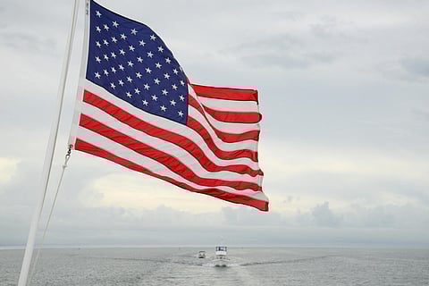 US Flag hoisting in a ship perhaps, but the ship is not visible, also a boat can be seen behind in the waters