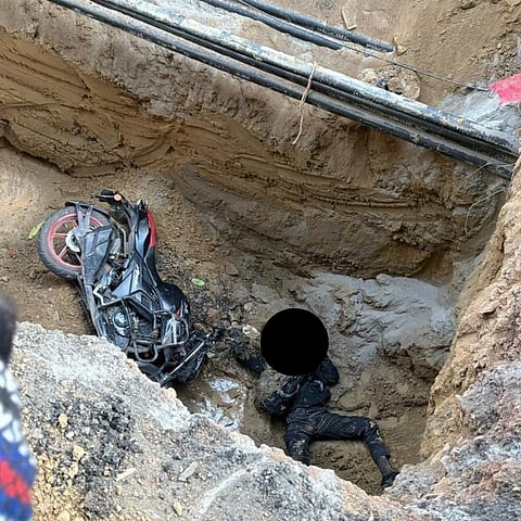 The uncovered muddy pit- biker lying dead beside his bike, biker's face blacked out