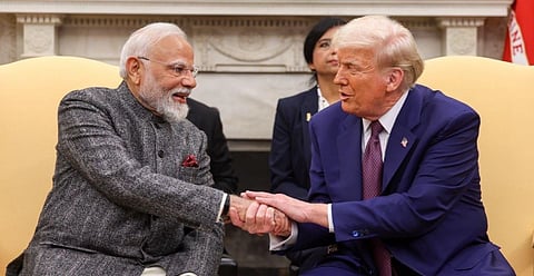 Images of PM Modi and President Trump seated, shaking hands warmly, both smiling. The man on the left wears a gray suit, while the man on the right wears a blue suit and red tie.