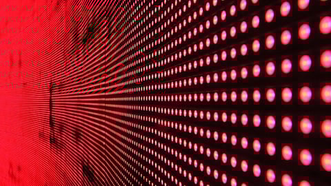 Close-up of an LED panel displaying red lights in a grid pattern, creating a vibrant, futuristic effect with depth and intense brightness.