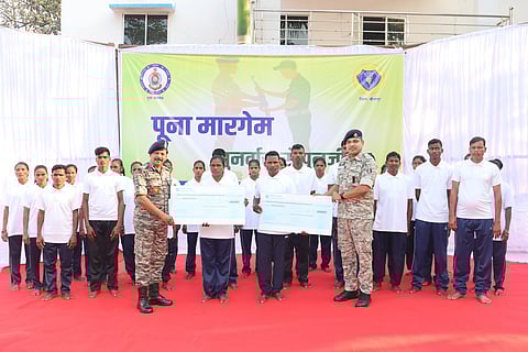 The cadres surrendering before the Police, the Police officials handing out financial assistance to two cadres, the rest standing behind
