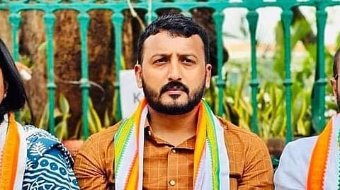 MLA Rahul Mamkootathil sits in front of a green fence while part of the Kerala Youth Congress.