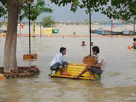 two people sit on a bench conversing as their surroundings are flooded