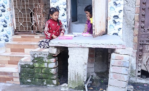 Children sitting outside their homes and playing, below is a naala