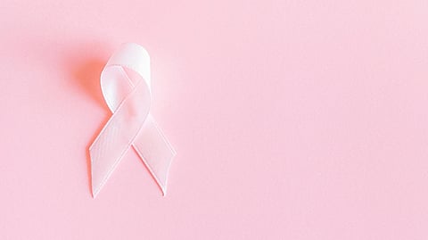 Pink ribbon symbolizing breast cancer awareness on a pastel pink background. The image conveys support and solidarity with a hopeful tone.