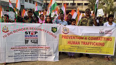 A BSF drive gainst human trafficking with a group of poeple holding up Indian flags and two banners reading 'Stop Human Trafficking' and  'Prevention and Combatting Human Trafficking'