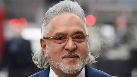 Vijay Mallya with his hairs up the background is blur he is wearing glasses