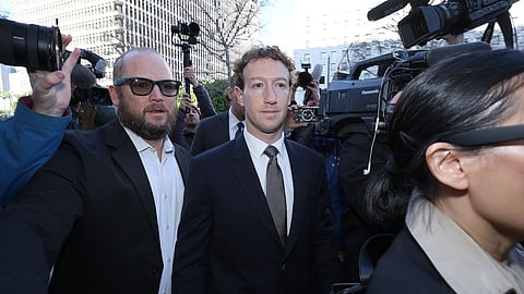 Meta CEO Mark Zuckerberg in a suit walks surrounded by media and security in a bustling urban setting. The tone is tense, with cameras capturing the moment.