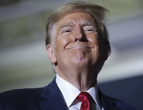 Close up image of President Donald trump smiling and looking downward. the background is blurred.