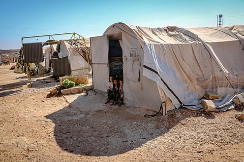 Refugee camps in a deserted ares with in one tent three childrens are sitting