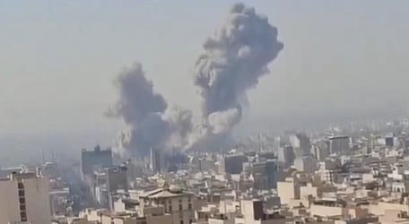 Image of a plume of smoke emerging after an attack on a city.  the image is of low resolution. 