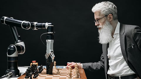 In the image A man with white beard and hair playing chess with a machine