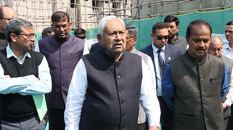 Nitish Kumar walking, looking confused, with people behind him