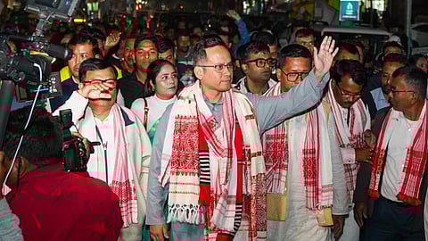 Gaurav Gogoi on a padyatra, waving at people with acrowd behind him