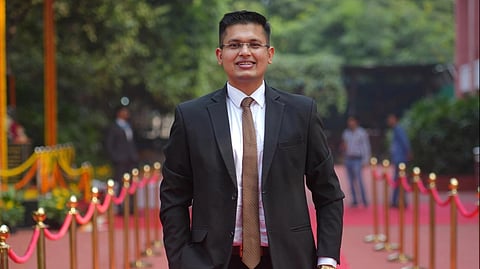 Anuj Agnihotri standing on a red carpet in a suit