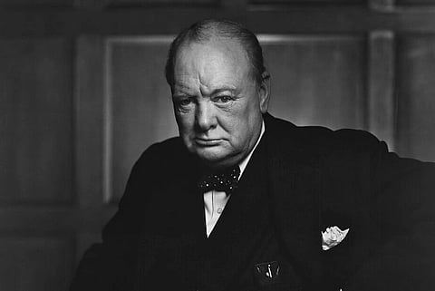 Black and white image of Winston Churchill in Canada, December 1941. he is wearing a black suit with a bow tie. 