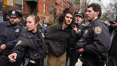 A man in a hoodie being arrested by NYC police officers