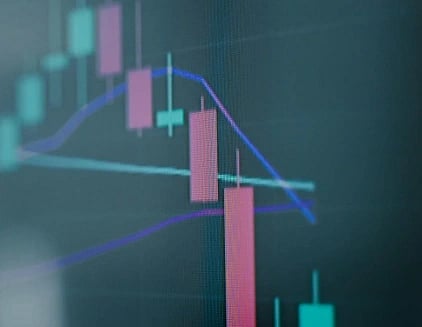 A stock market graph displaying red and green candlesticks with blue trend lines on a dark background, conveying a sense of market volatility.
