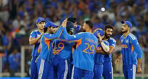 Image of team India players hugging and celebrating during the  ICC Men’s T20 World Cup. A group of Indian cricket players celebrates on the field in blue uniforms with orange accents, displaying joyful camaraderie and excitement.