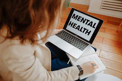 A woman looking at her laptop that displays the text "Mental Health"