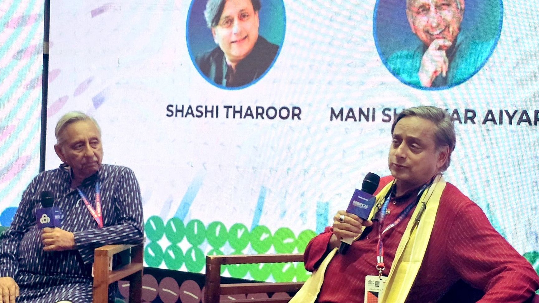Mani Shankar Aiyar and Shashi Tharoor sitting next to each other, holding mics