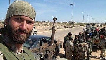 In the image army soldiers are shown with jeep and cars one soldier is clicking the picture he is looking at the camera holding a gun