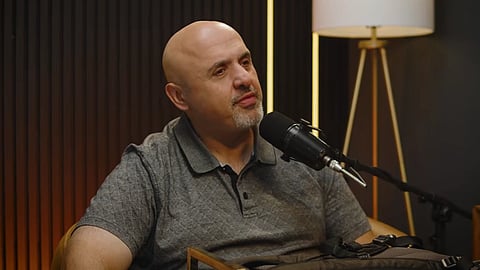 In the image Sam Shamoun  is shown speaking in a mike in a podcast