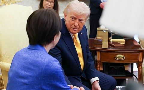 Image of Donald trump shaking hands with Takaichi Sanae at the White house. they are both seated next to each other. 