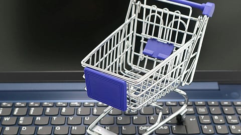 In the image a laptop is shown above that a trolly is shown signifying e commerce 