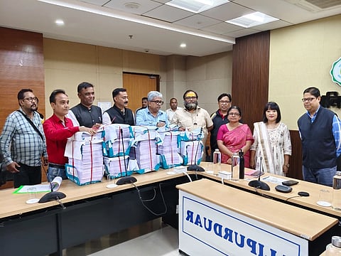 Many election officers stand behind large bundles of papers while preparing for the 2026 Bengal Assembly Election