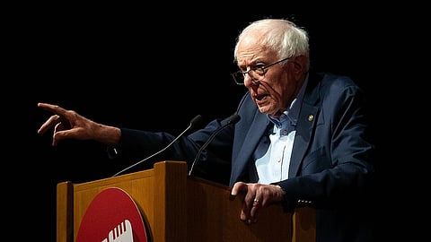 Bernie Sanders standing behind a podium, pointing a finger