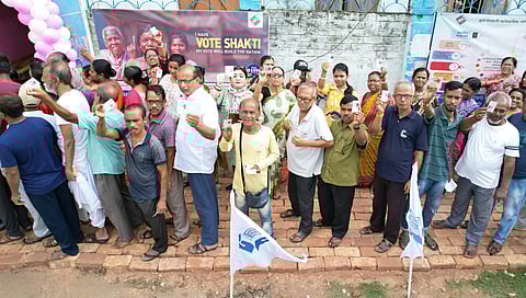 Voters in a queue showinf off their voter IDs at the polling station of 18 Basirhat PC of North 24 Parganas district, West Bengal, June 2024.