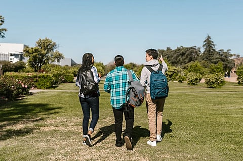 Three students walking on a ground in a university