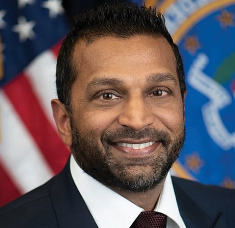 Image of official portrait of FBI director Kash Patel in a formal attire. behind him is the national flag of USA and FBI logo.