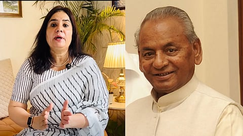 A woman in a striped saree speaks expressively while seated indoors beside a well-lit lamp and greenery. An elderly man, smiling warmly, wears a white suit.