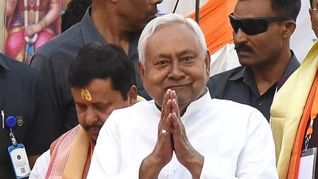 In the image Nitish kumar is shown joining his hands behind him are many other people including his bodyguards