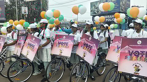 Children on cycles with posters reading 'VOTE' while holding tri-colour balloons ahead of the 2026 Bengal Election