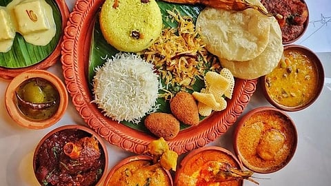 A vibrant Indian thali with rice, puris, various curries, and desserts on a banana leaf. The dishes are arranged on a clay platter, inviting and colorful.